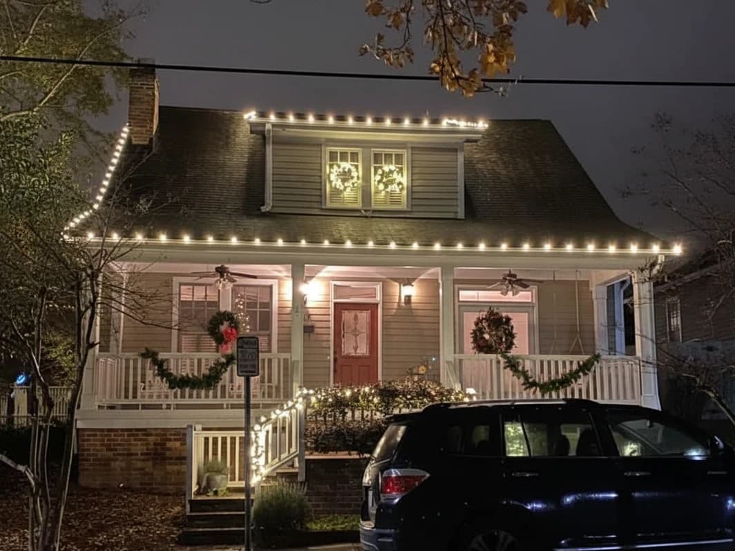 Holiday lights installed along a home roofline with wreaths and garland
