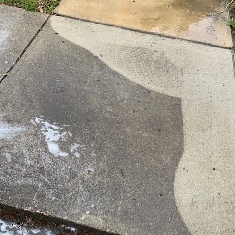 Concrete being cleaned with a visible treated area