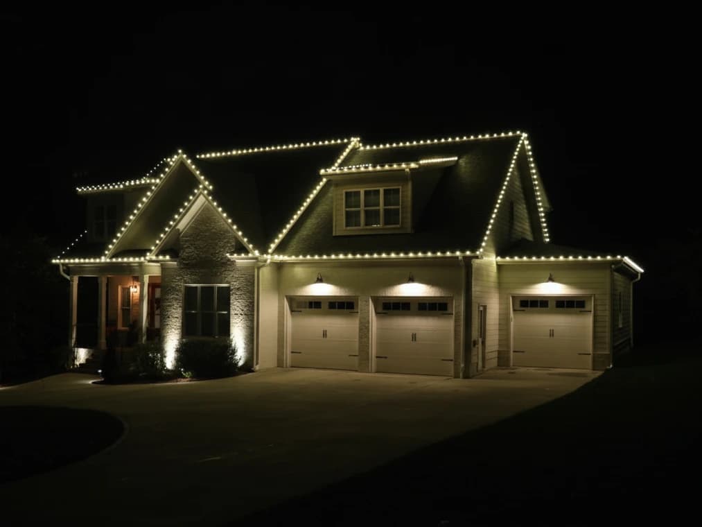 Warm white holiday lights installed along the roofline of a home